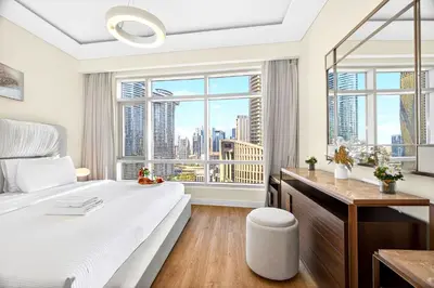 a bedroom with a large bed with a desk and a window at Trendy 2BR Direct Mall Access Burj View High Floor in Dubai