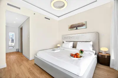 a white bedroom with a bed with a bowl of fruit on it at Trendy 2BR Direct Mall Access Burj View High Floor in Dubai