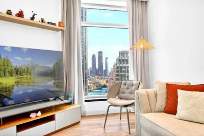 a living room with a large screen tv and a chair at Trendy 2BR Direct Mall Access Burj View High Floor in Dubai