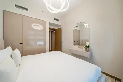 a white bedroom with a large bed and a mirror at Modern 2BR Canal-Side Elegance in Dubai