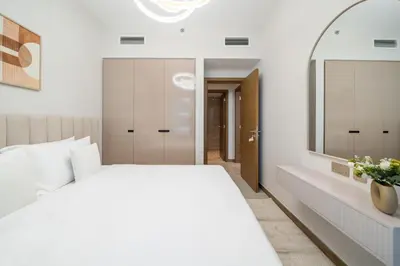 a bedroom with a white bed and a mirror at Modern 2BR Canal-Side Elegance in Dubai