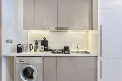 a white kitchen with a sink and a washing machine at Modern Boutique Studio with Burj Khalifa View in Dubai