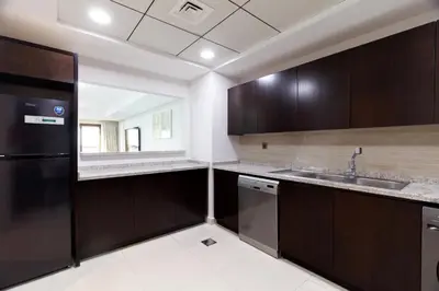 a kitchen with brown cabinets and a sink and a mirror at Charming Sea View 2BDR, Beach and Pool Access in Dubai