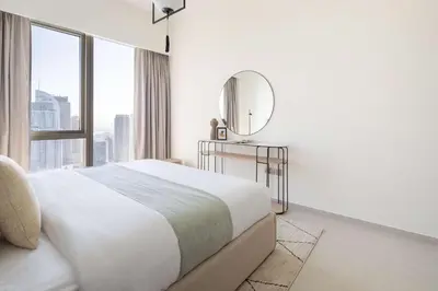 a white bedroom with a large bed and a mirror at Frank Porter - Grande Signature Residence in Dubai