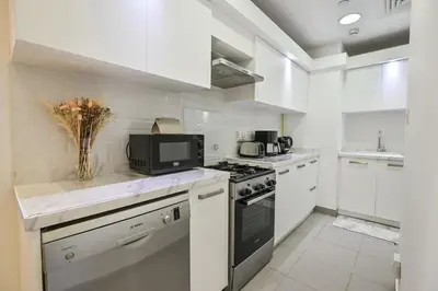 a white kitchen with a stove and a microwave at Azure Residences a Beachfront Getaway on Palm Jumeirah in Dubai
