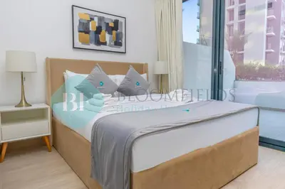 a bedroom with a bed with blue and white pillows at Bloomfields Stylish 1br In Azizi Riviera in Dubai