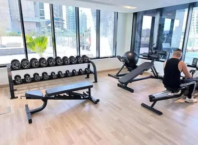 a man exercising in a gym with exercise equipment at Sunset View Overlooking Burj Khalifa and Canal View in Dubai