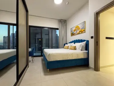 a bedroom with a blue bed and a large window at Sunset View Overlooking Burj Khalifa and Canal View in Dubai