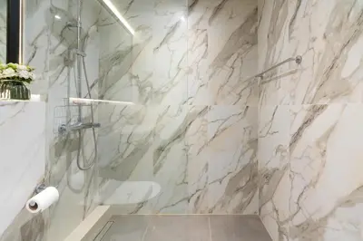 a bathroom with a shower with marble walls at White Sage Spacious 1BR at Marina Promenade in Dubai