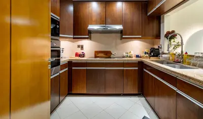 a kitchen with wooden cabinets and a sink at Usmans Brand New Duplex Apartment 5 Bedrooms Dubai Marina Trident Bayside 4 Rooms with 4 En-suite Washrooms in Dubai