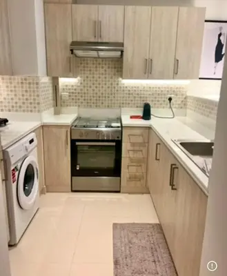 a kitchen with a stove and a washing machine at 1 Bedroom by the beach with free Rooftop pool access in Dubai
