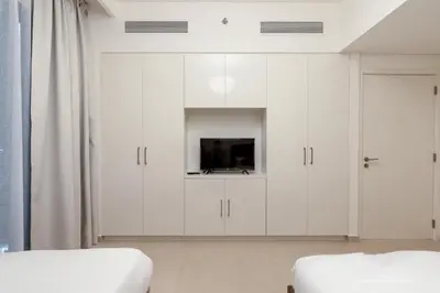 a white bedroom with white cabinets and a tv at 3 Bedrooms Apartment in Downtown Views - Dubai Burj Khalifa View in Dubai