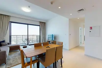 a dining room with a table and a large window at Vacay Lettings -2 bed at Park ridge Dubai Hills in Dubai