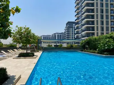 a large swimming pool with chairs and a building at Vacay Lettings -2 bed at Park ridge Dubai Hills in Dubai