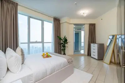 a bedroom with a large white bed and large windows at Classy Upgraded - High Floor - Prime Location in Dubai