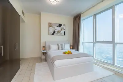 a bedroom with a bed and a large window at Classy Upgraded - High Floor - Prime Location in Dubai