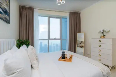 a bedroom with a white bed with a large window at Classy Upgraded - High Floor - Prime Location in Dubai