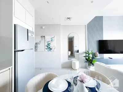 a white dining room with a table and a refrigerator at Burj Royale Luxury One-Bedroom with City Views in Dubai