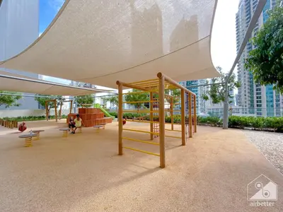 a playground with a canopy and benches and buildings at Burj Royale Luxury One-Bedroom with City Views in Dubai