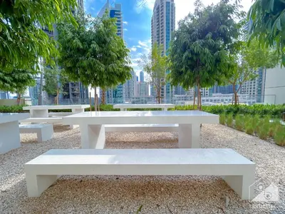 a group of white benches in a park with a city skyline at Burj Royale Luxury One-Bedroom with City Views in Dubai