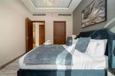 a bedroom with a large bed with a blue blanket at White Sage New Large 1BR at JVC in Dubai