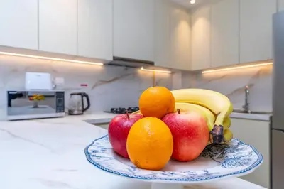 a plate with apples oranges and bananas on a kitchen counter at White Sage New Large 1BR at JVC in Dubai