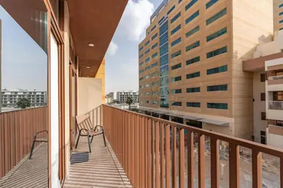 a balcony with two chairs and two buildings at White Sage New Large 1BR at JVC in Dubai