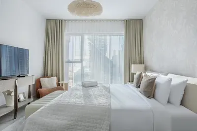 a white bedroom with a large bed and a window at Ultra-Luxury 2BR at La Vie Iconic Sea Views in Dubai