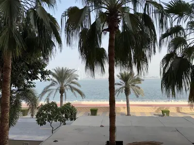 a group of palm trees in front of the ocean at Royal Amwaj-Anantara residence South in Dubai