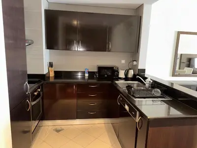 a kitchen with brown cabinets and a counter top at Royal Amwaj-Anantara residence South in Dubai
