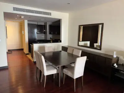 a dining room with a black table and white chairs at Royal Amwaj-Anantara residence South in Dubai
