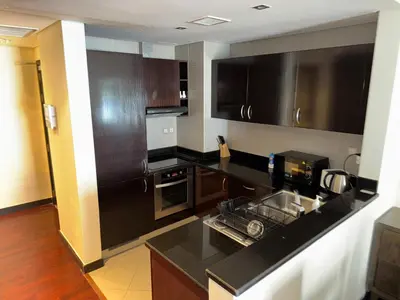 a kitchen with a black counter top and wooden cabinets at Royal Amwaj-Anantara residence South in Dubai