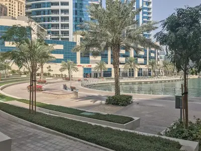 a park with palm trees in front of a building at Frank Porter - Marina Quays East Tower in Dubai
