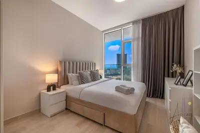 a bedroom with a bed and a large window at Cityview Haven 1BR Modern Flat in Bloom Heights in Dubai