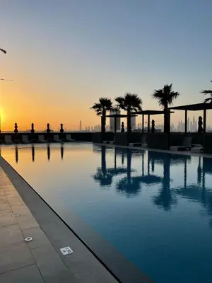 a swimming pool with palm trees on a building at Cityview Haven 1BR Modern Flat in Bloom Heights in Dubai