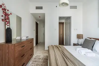 a bedroom with a large bed with a wooden dresser at ShoresInn - A sublime stay in Dubai Marina in Dubai