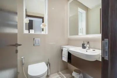 a bathroom with a toilet and a sink and mirror at Downtown Elegance - 1BR Apartment with Unmatched Burj Khalifa Views in Dubai