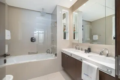 a bathroom with two sinks and a tub and a shower at Downtown Elegance - 1BR Apartment with Unmatched Burj Khalifa Views in Dubai
