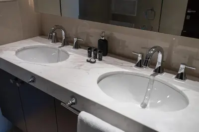 two sinks in a bathroom with two faucets at Downtown Elegance - 1BR Apartment with Unmatched Burj Khalifa Views in Dubai