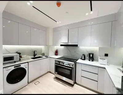 a white kitchen with a stove and a dishwasher at Binghatti Heights JVC in Dubai