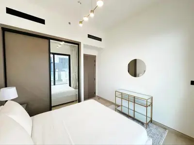 a white bedroom with a bed and a mirror at Binghatti Heights JVC in Dubai