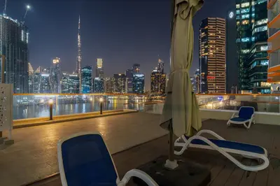 a room with two chairs and an umbrella on a roof at Stunning Waterfront Burj Views with Pool & Gym, Sleeps 6 in Dubai
