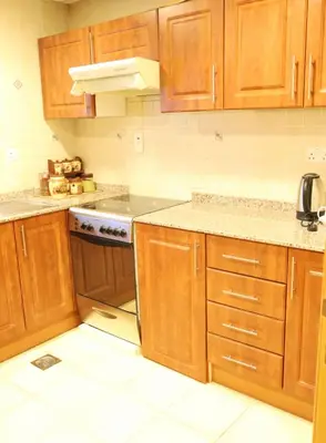 a kitchen with wooden cabinets and a stove top oven at Luxury Apartment by oima leasing property in Dubai