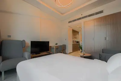 a bedroom with a white bed and chairs and a television at Creek view studio deleguest in Dubai