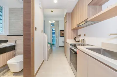 a kitchen with white counters and wooden cabinets at Charm Studio Fully Furnished with Style in Dubai