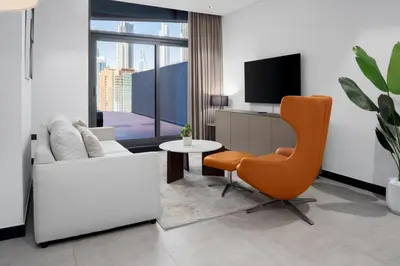 a living room with a couch and a chair and a tv at Waves - Spacious 2BR Apartment with Burj Views & Terrace in Dubai