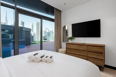 a hotel room with a bed and a flat screen tv at Waves - Spacious 2BR Apartment with Burj Views & Terrace in Dubai