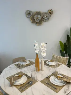 a dining room table with plates and glasses and flowers at 2 Bedrooms - District One Residences 13 in Dubai