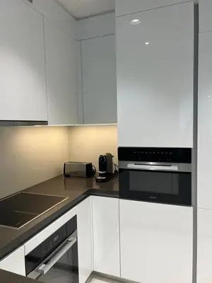 a kitchen with white cabinets and a black appliance at 2 Bedrooms - District One Residences 13 in Dubai