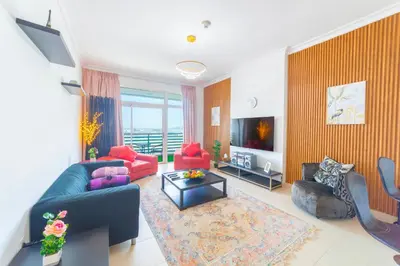 a living room with a blue couch and red chairs at An Elegant Fully Furnished 1 Bedroom Apartment in Clayton Residency, Business Bay, Dubai in Dubai